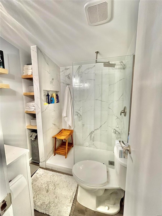 bathroom with a marble finish shower and toilet