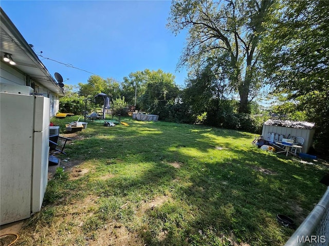 view of green lawn featuring a storage shed and an outbuilding