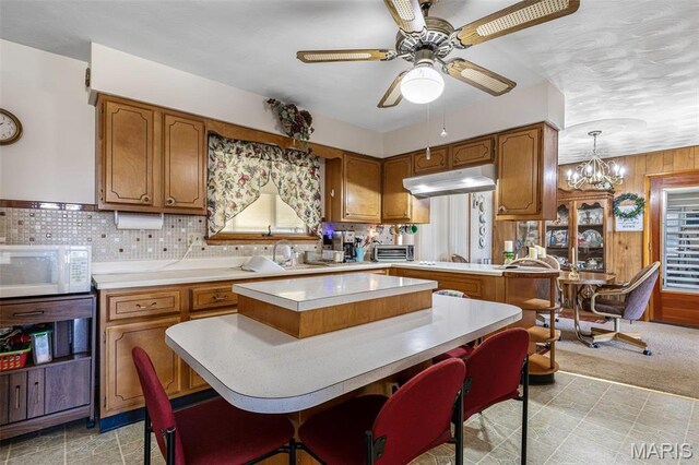 113 S Madison St, Desloge, MO 63601 - kitchen with brown cabinets, white microwave, light countertops, ceiling fan, and wooden walls