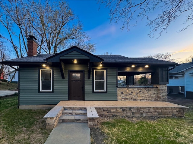 view of front of home with a chimney and roof with shingles