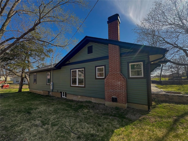view of side of home featuring a chimney and a yard