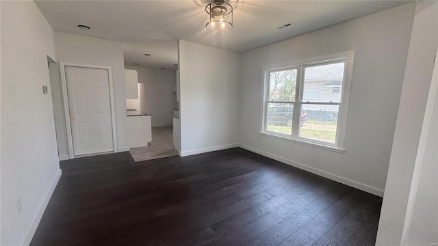 empty room featuring dark wood-type flooring and baseboards