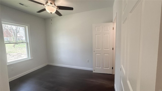 empty room featuring dark wood-style flooring, a ceiling fan, and baseboards