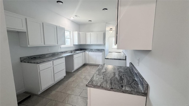 kitchen with white cabinets, light tile patterned floors, and a sink