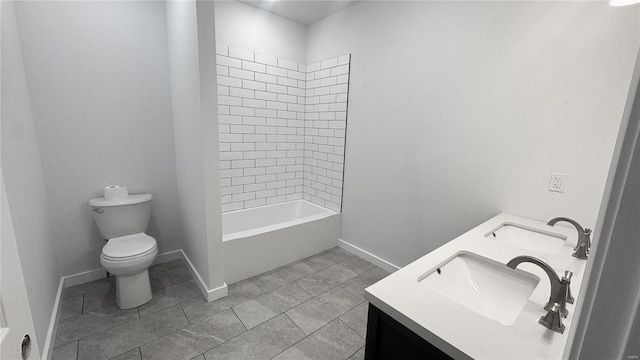 bathroom featuring toilet, baseboards, double vanity, and tile patterned flooring