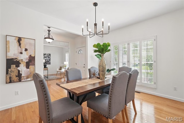 dining room with a chandelier, baseboards, and light wood-style flooring