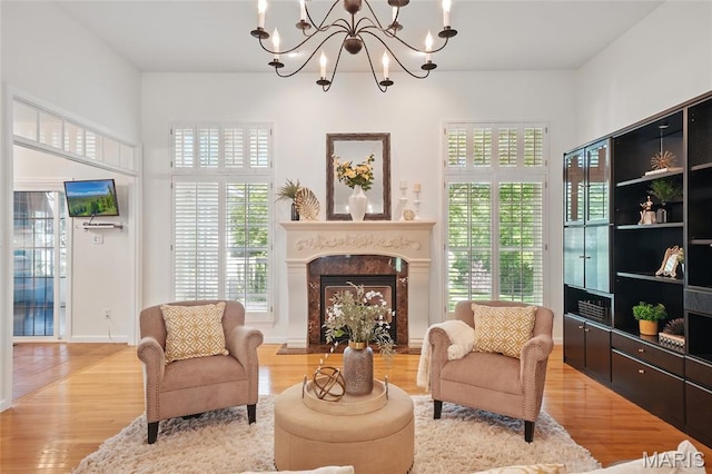 sitting room featuring wood finished floors, a fireplace, and a chandelier