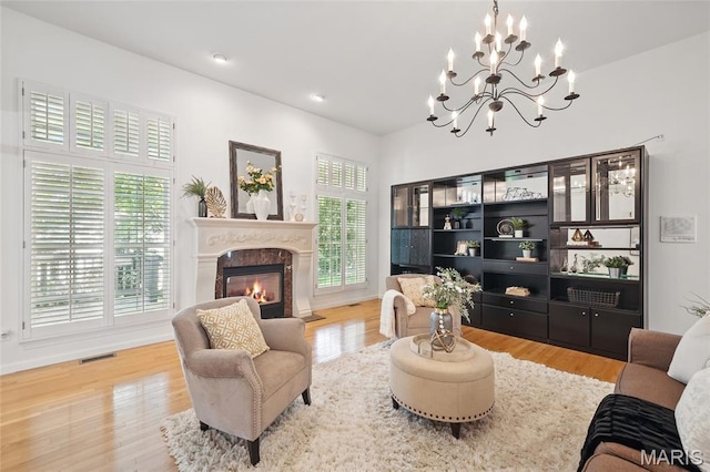 living area with a chandelier, plenty of natural light, a fireplace, wood finished floors, and recessed lighting