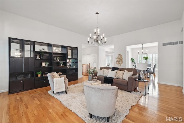 living room with a chandelier, light wood finished floors, and baseboards