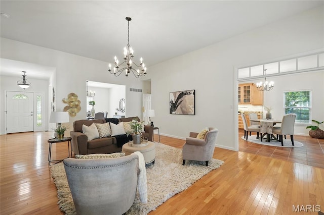living area with a chandelier, light wood finished floors, and baseboards
