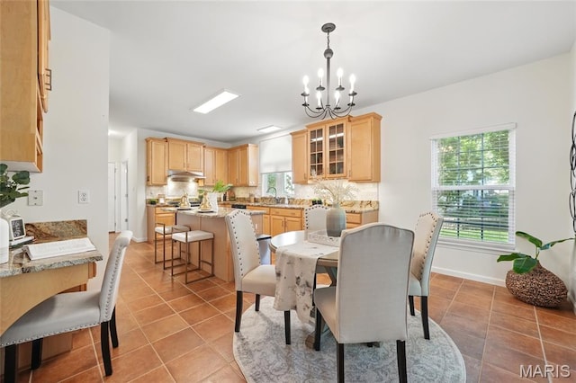 dining space with a chandelier, light tile patterned floors, and baseboards