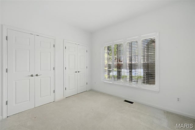 unfurnished bedroom with multiple closets and carpet