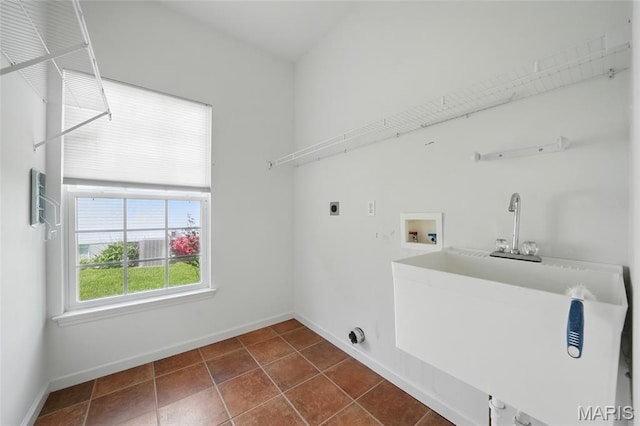 clothes washing area with washer hookup, baseboards, electric dryer hookup, and dark tile patterned flooring