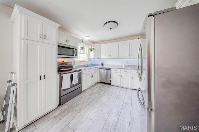 24478 Trolley Ln, Saint Robert, MO 65584 - kitchen with stainless steel appliances, a sink, white cabinetry, and wood tiled floors