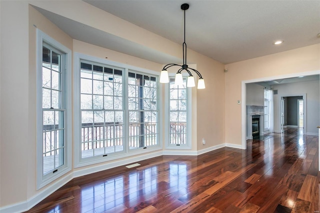 unfurnished dining area with baseboards, wood finished floors, a chandelier, and recessed lighting