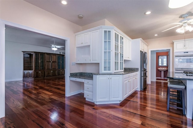 kitchen featuring a ceiling fan, freestanding refrigerator, dark wood-style flooring, glass insert cabinets, and white cabinets