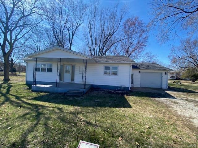 view of front of property featuring dirt driveway, covered porch, an attached garage, and a front yard
