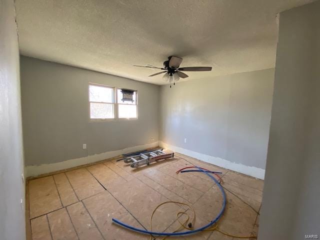 empty room featuring ceiling fan, baseboards, and a textured ceiling