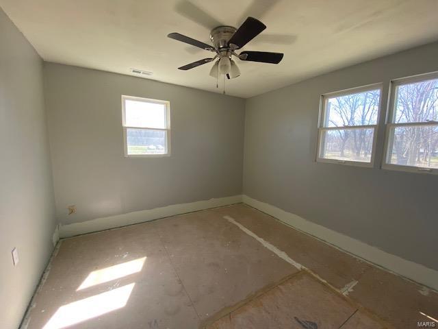 unfurnished room with healthy amount of natural light, baseboards, and a ceiling fan