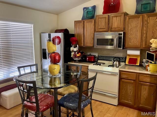 4304 Inlet Isle Dr, Florissant, MO 63034 - kitchen featuring stainless steel appliances, light wood-style flooring, light countertops, brown cabinets, and vaulted ceiling