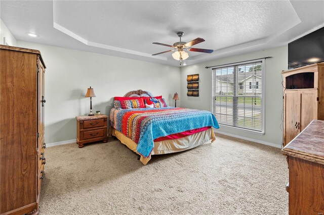 bedroom with a raised ceiling, light colored carpet, baseboards, and a textured ceiling