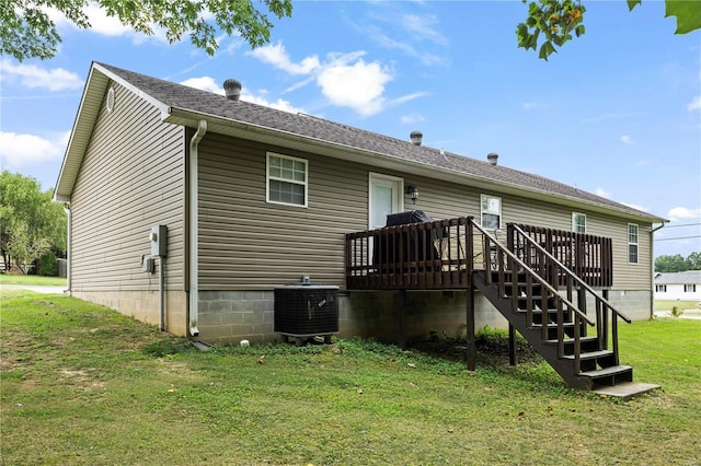 rear view of property with cooling unit, a deck, a lawn, and a shingled roof