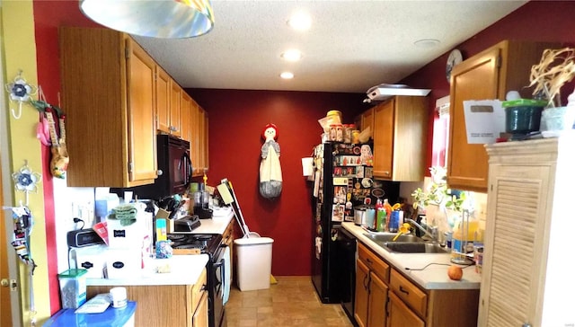 kitchen with a sink, black appliances, light countertops, recessed lighting, and brown cabinetry
