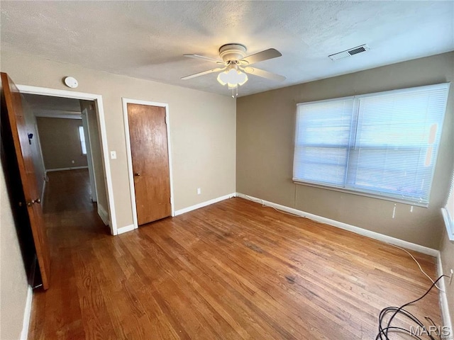 unfurnished bedroom featuring baseboards, wood finished floors, ceiling fan, a textured ceiling, and a closet
