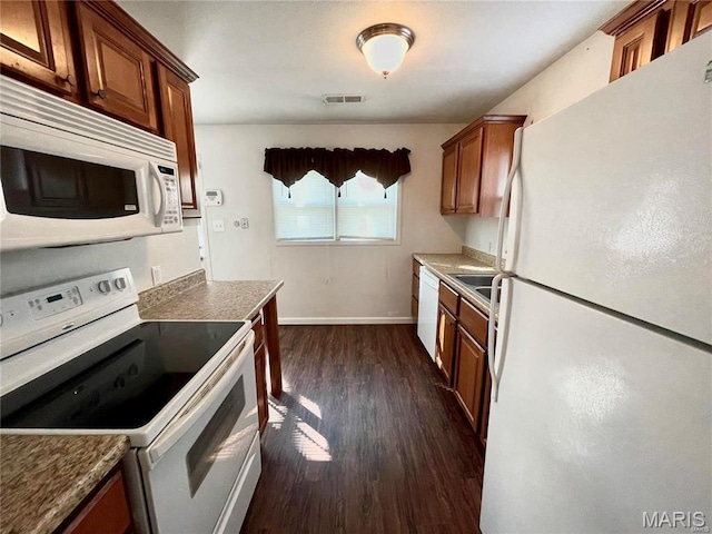 kitchen with white appliances, dark wood-style floors, brown cabinetry, and baseboards