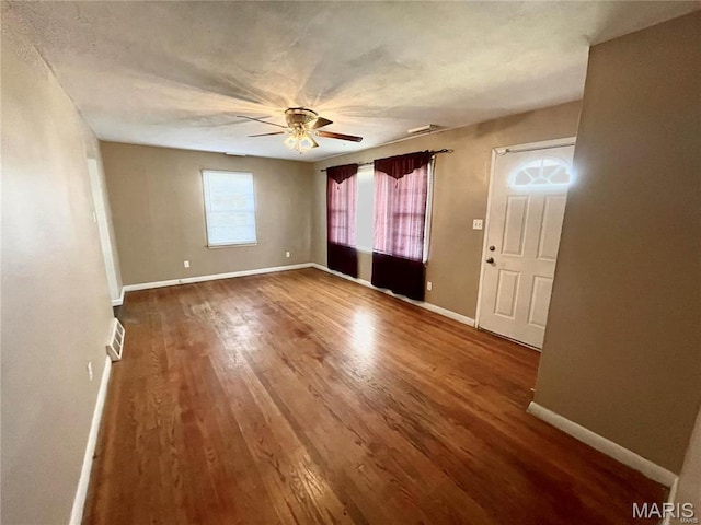 unfurnished room with a ceiling fan, wood finished floors, and baseboards