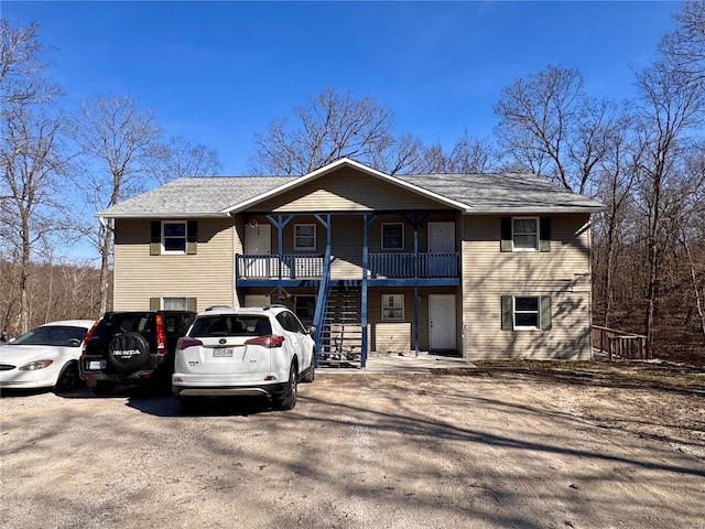 multi unit property featuring stairway, a porch, and a shingled roof