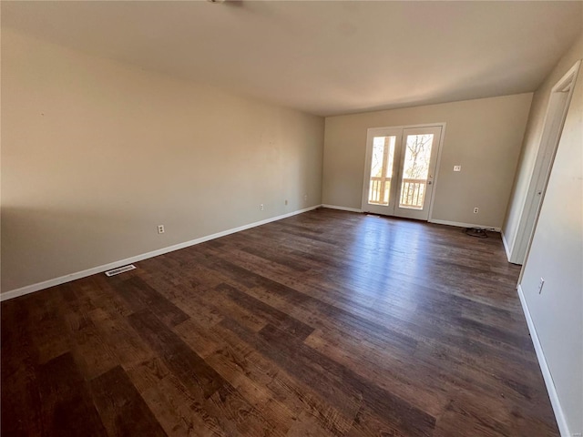 spare room featuring baseboards and dark wood-style floors