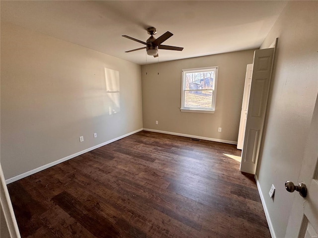 unfurnished room featuring a ceiling fan, dark wood finished floors, and baseboards