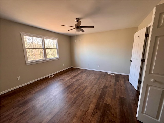 unfurnished room featuring ceiling fan, dark wood-type flooring, and baseboards