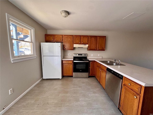 kitchen featuring stainless steel appliances, a sink, under cabinet range hood, brown cabinets, and light countertops