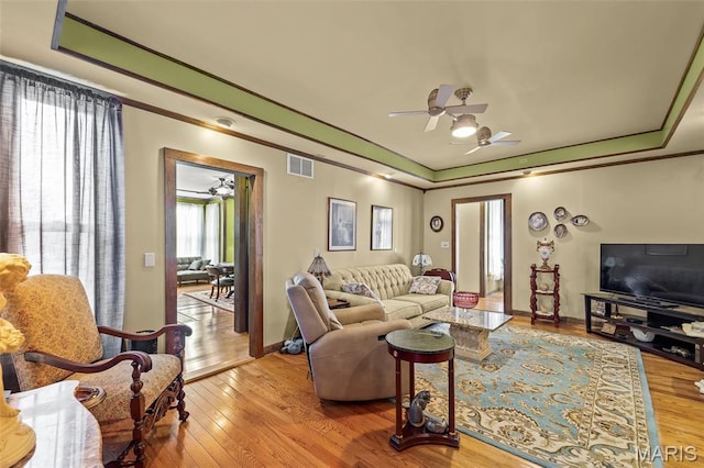 705 Jefferson St, Fulton, MO 65251 - living area with a ceiling fan, a raised ceiling, light wood-style flooring, crown molding, and baseboards