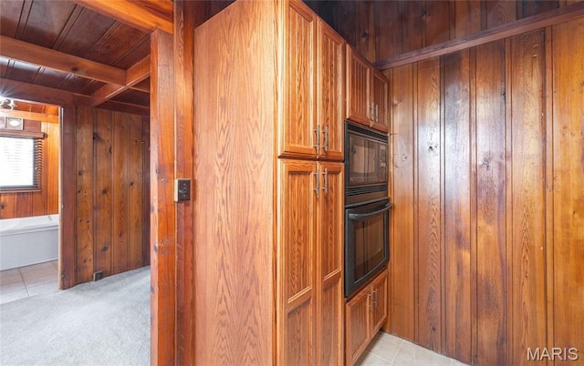 1382 Osage Rd, Cuba, MO 65453 - kitchen featuring wooden walls, black appliances, wooden ceiling with exposed beams, brown cabinetry, and light colored carpet