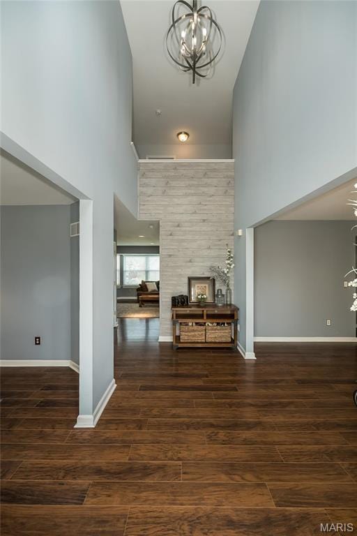 hallway with a chandelier, a high ceiling, wood finished floors, and baseboards