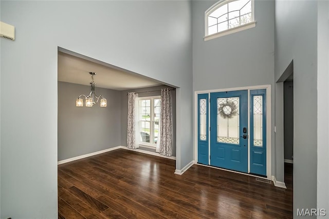 foyer entrance featuring a chandelier, a high ceiling, dark wood-type flooring, and baseboards