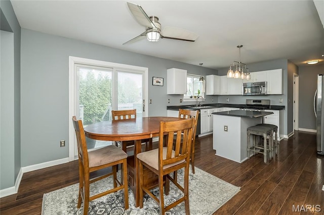 dining space featuring dark wood-style flooring, ceiling fan, and baseboards
