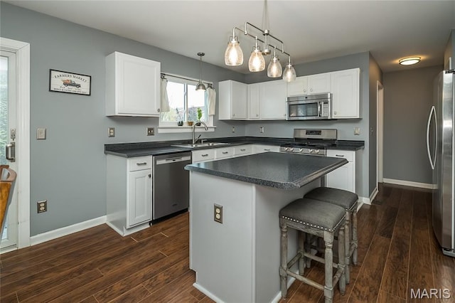 kitchen featuring stainless steel appliances, a sink, dark countertops, and dark wood finished floors