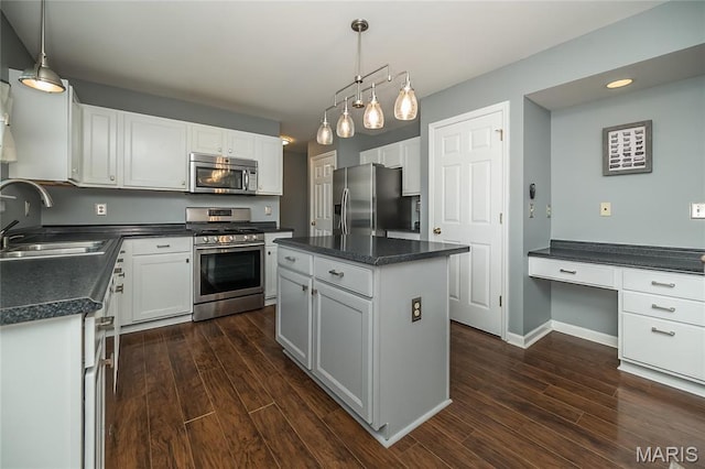 kitchen with appliances with stainless steel finishes, a sink, dark countertops, dark wood finished floors, and recessed lighting