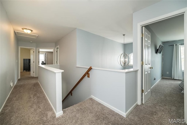 hall with an upstairs landing, carpet flooring, and baseboards