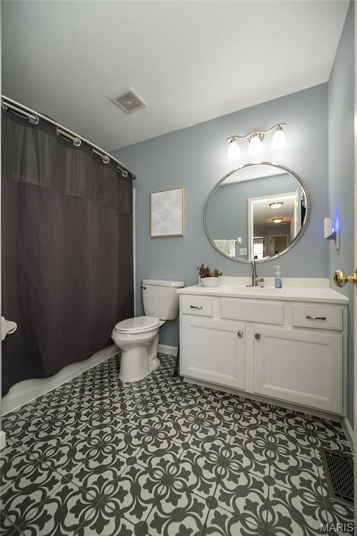 bathroom featuring toilet, vanity, baseboards, and a shower with curtain