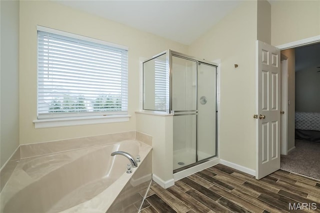 ensuite bathroom with wood finished floors, a shower stall, a bath, and baseboards
