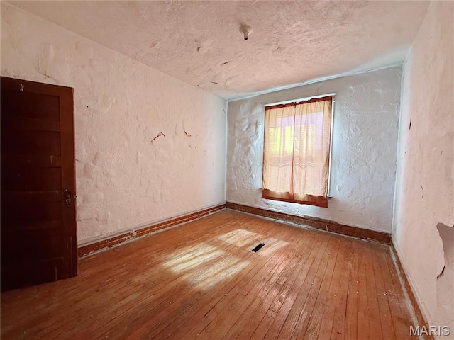4753 Maffitt Ave, Saint Louis, MO 63113 - empty room with hardwood / wood-style flooring, a textured ceiling, a textured wall, and baseboards