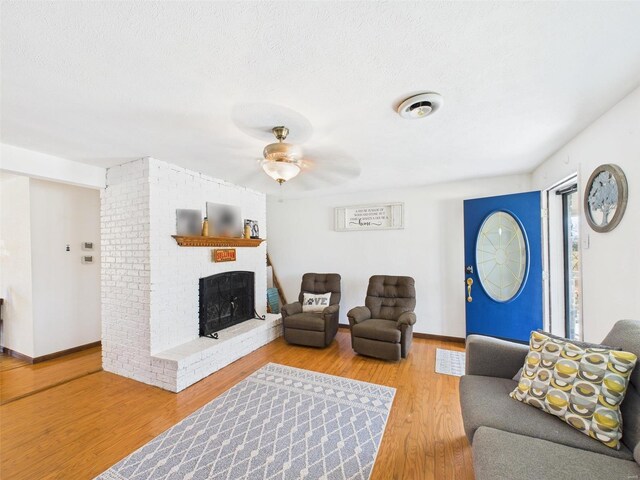 16892 Beaufort Rd, Crocker, MO 65452 - living room featuring a brick fireplace, ceiling fan, wood finished floors, a textured ceiling, and baseboards