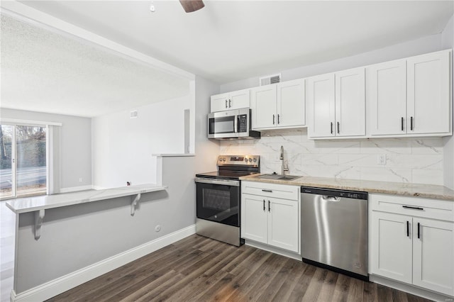 2781 Blackforest Dr Unit B, Saint Louis, MO 63129 - kitchen featuring appliances with stainless steel finishes, a sink, tasteful backsplash, dark wood-style floors, and white cabinetry