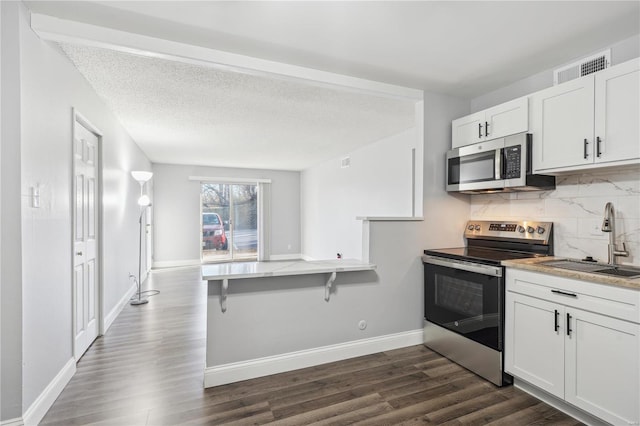 2781 Blackforest Dr Unit B, Saint Louis, MO 63129 - kitchen featuring stainless steel appliances, a sink, decorative backsplash, dark wood-type flooring, and white cabinets