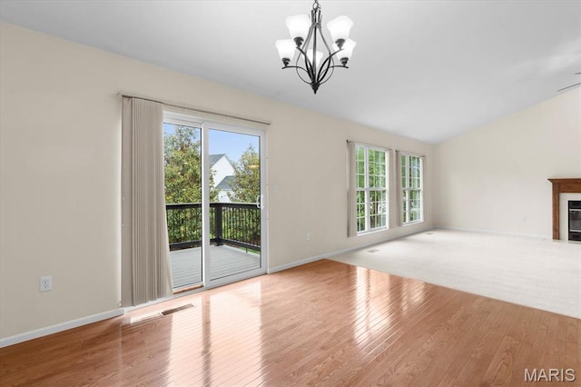 724 E Wesley Dr, Ofallon, IL 62269 - unfurnished living room featuring a chandelier, wood finished floors, vaulted ceiling, a fireplace with flush hearth, and baseboards